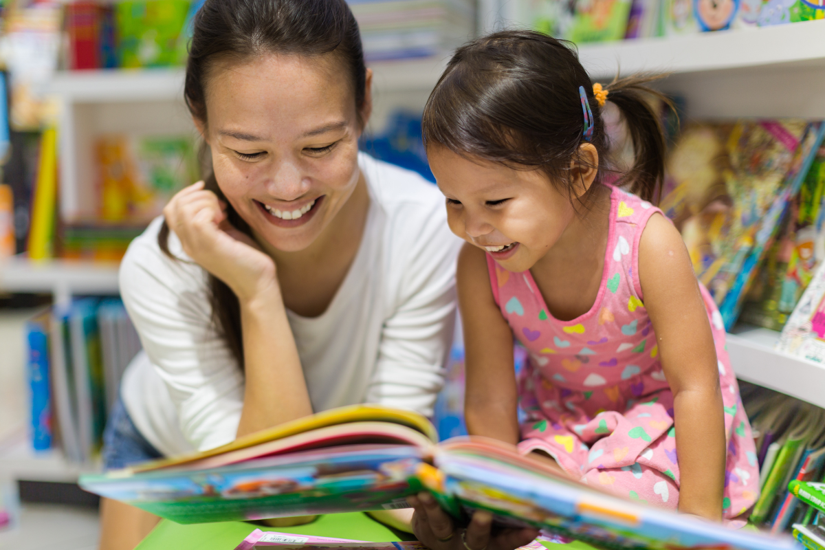 Mother and daughter lying on floor reading a book together