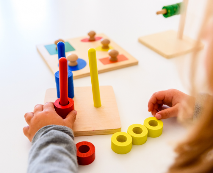 Child sorting different coloured wooden beads on matching coloured rods