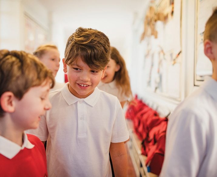 Children walking in school corridor talking and smiling