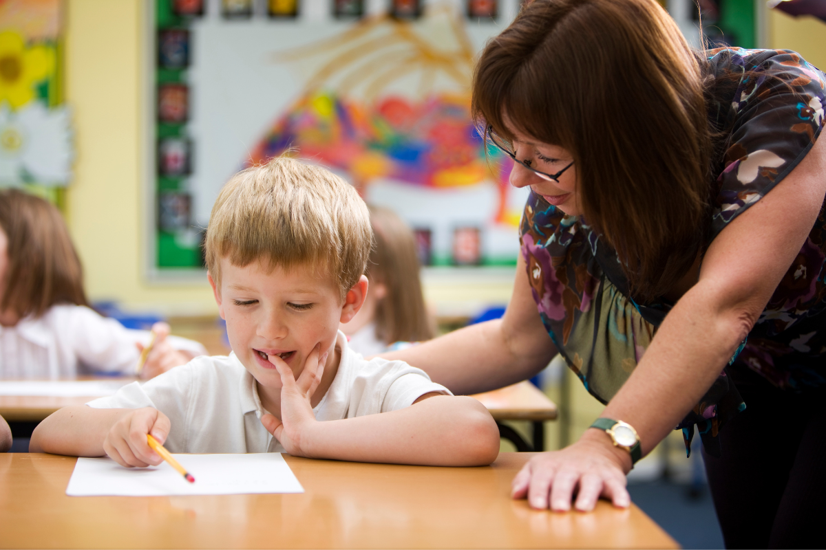 Teacher comforting young student struggling with class work