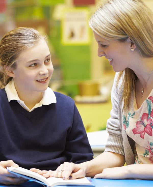 Teacher working with young student at desk