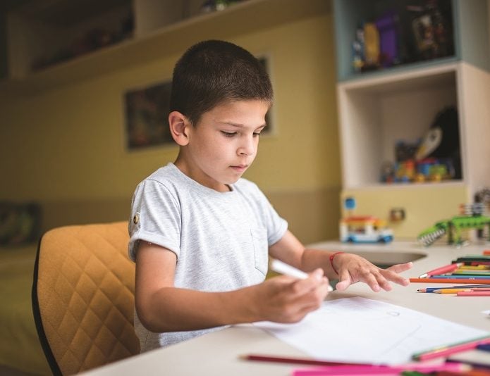 Child colouring at desk in bedroom
