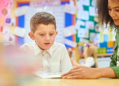 Teacher reading with student in classroom