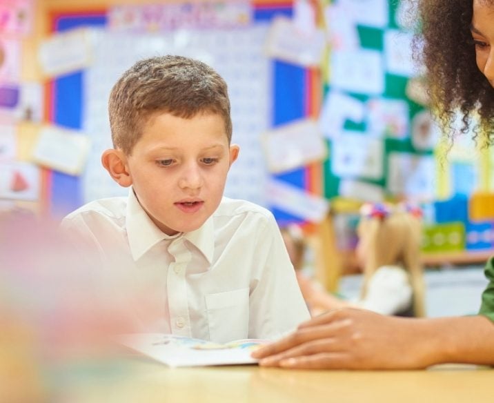 Teacher reading with student in classroom