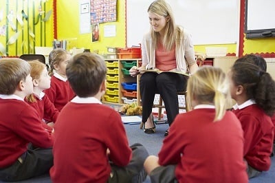 Teacher sitting down talking to group of students