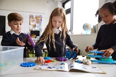 Child working with peers at desk in classroom