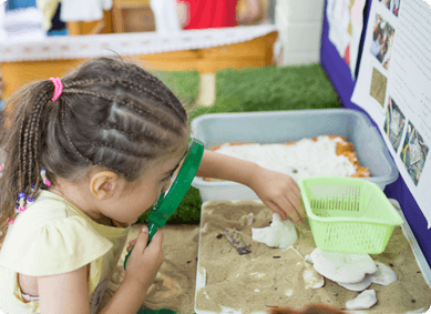 Child looking at sand through magnifying glass