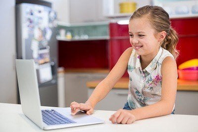 Young girl sitting at laptop smiling