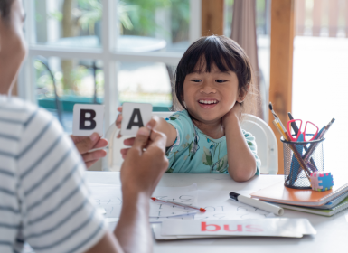 Parent holding up letter flashcards for child