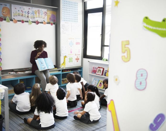 Kindergarten students sitting on the floor listening to teacher