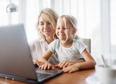 Smiling mother and child uses laptop at home