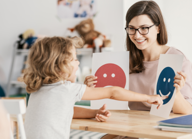 Psychologist sitting with child looking at pictures of emotions