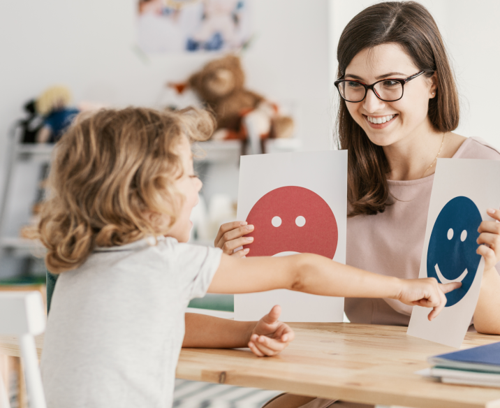 Psychologist sitting with child looking at pictures of emotions