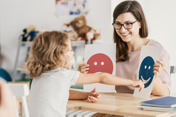 Psychologist sitting with child looking at pictures of emotions