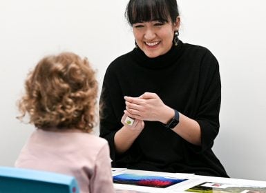 Speech pathologist playing game with young girl at table