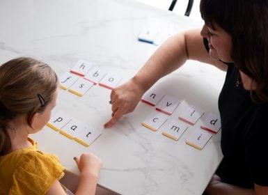 Teacher working with student to make words with letter cards