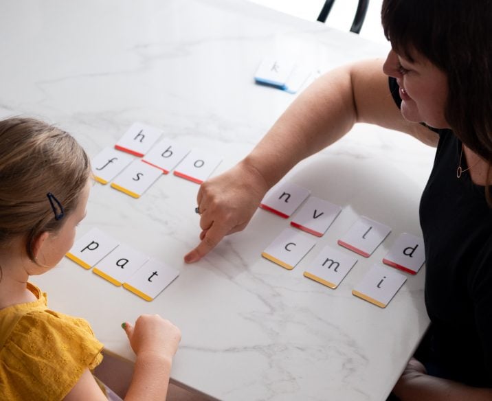 Teacher working with student to make words with letter cards