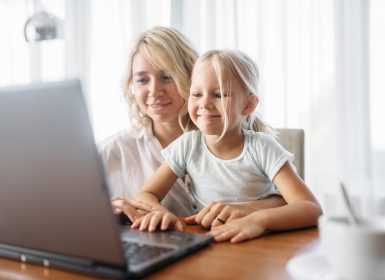 Smiling mother and child uses laptop at home