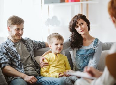 Mum and dad sitting with young son on couch