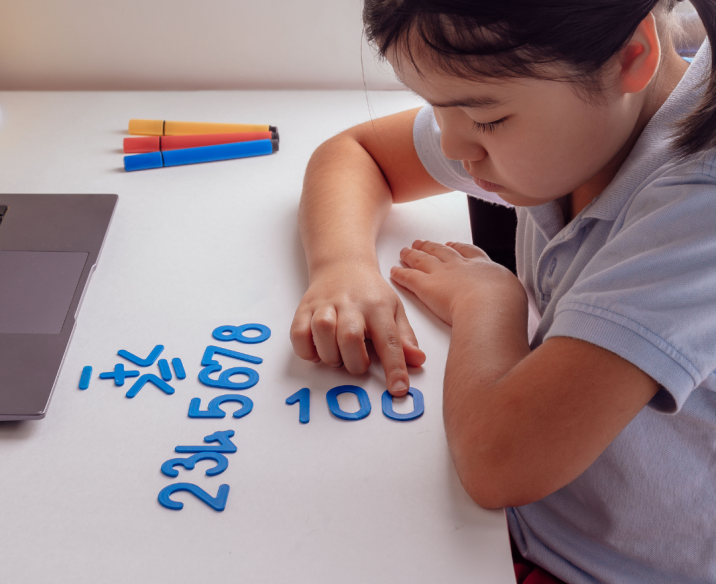 Primary school student playing with number cut outs on desk