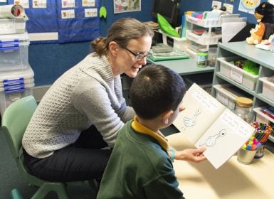 Learning Links speech pathologist reading with primary aged child in classroom