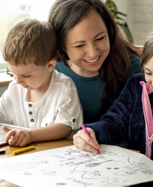 Mum sitting with son and daughter colouring in