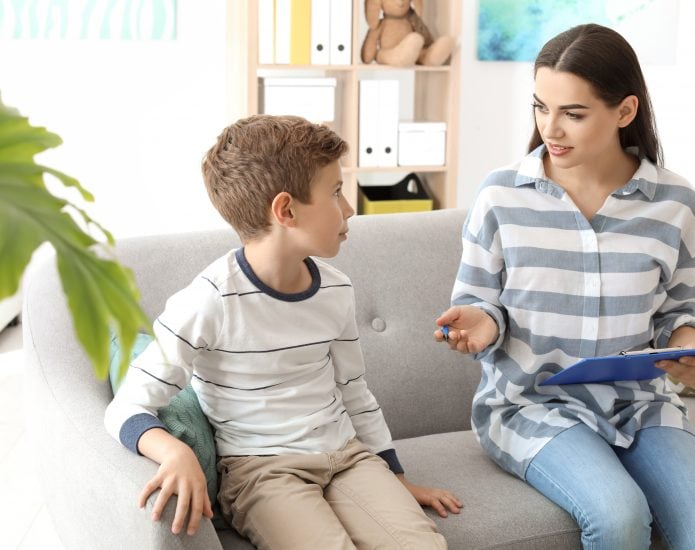 Psychologist and child sitting on couch talking