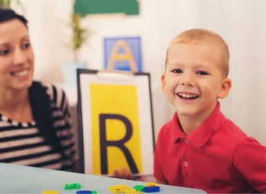 Young boy looking at paper with the letter 'R'