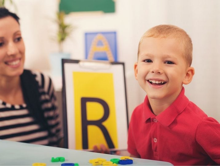 Young boy looking at paper with the letter 'R'