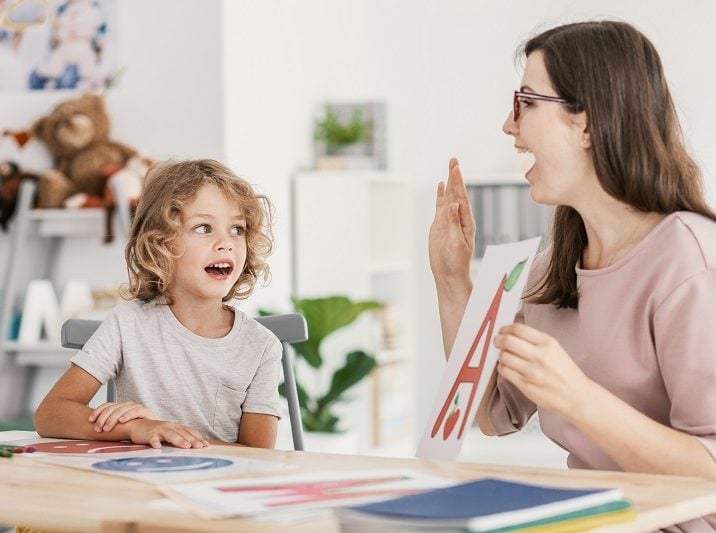 Speech therapist teaching letter pronunciation to a young boy