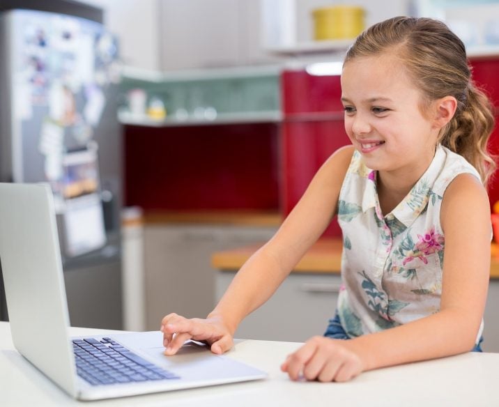 Young girl sitting in front of laptop at home