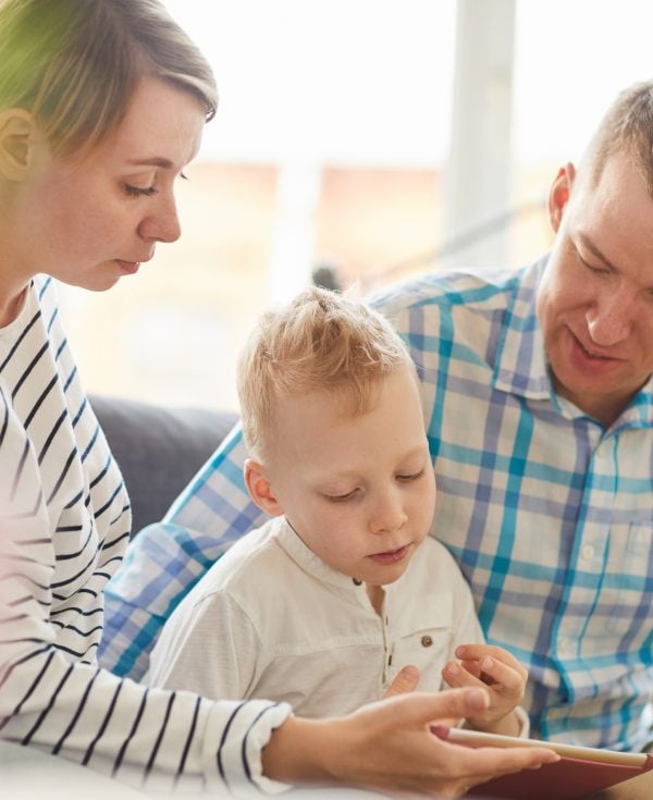 Little boy sitting with mum and dad looking at tablet