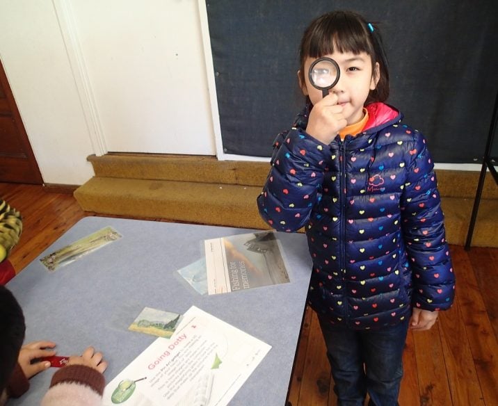 Child holding up magnifying glass to eye