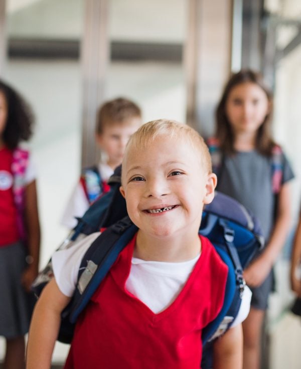 Young boy with disability walking with friends at school