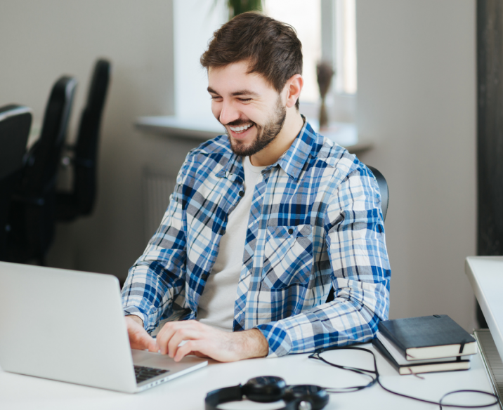 Man sitting in front of laptop at desk smiling