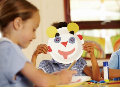 Student holding up face made of craft materials