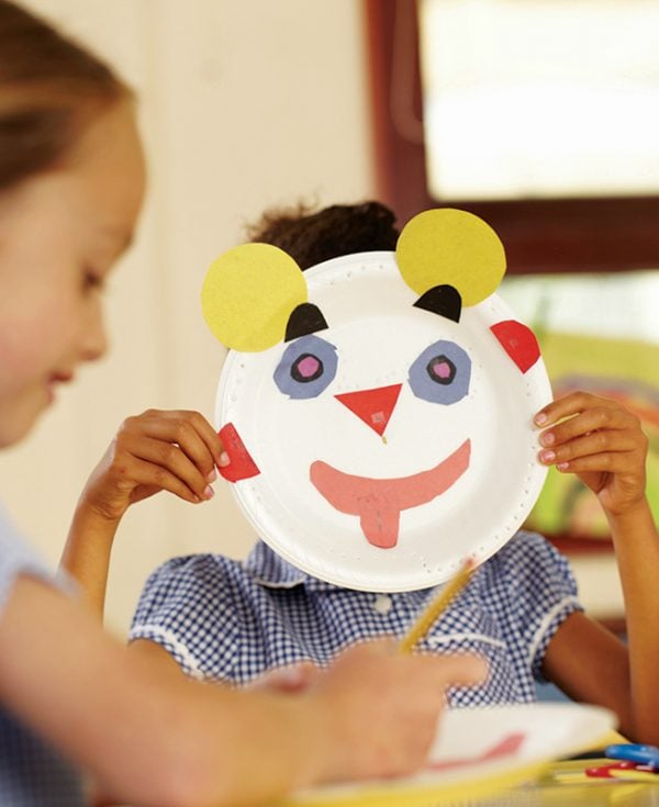 Student holding up face made of craft materials