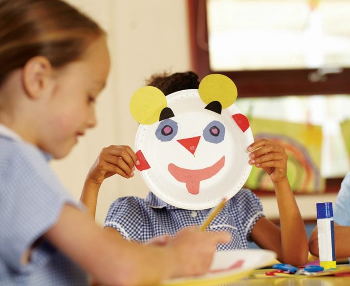 Student holding up face made of craft materials