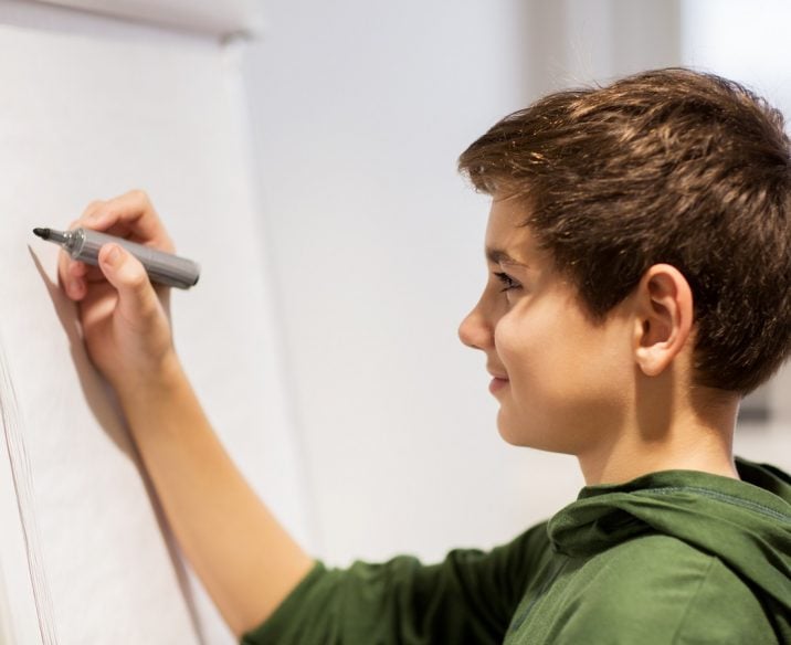 Boy in social skills program writing on white board