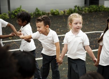 Young school students hold hands in playground