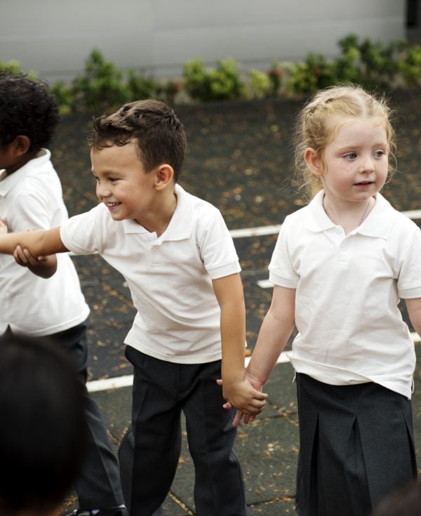 Young school students hold hands in playground