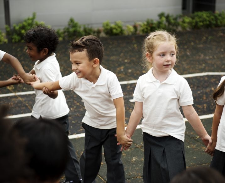 Young school students hold hands in playground