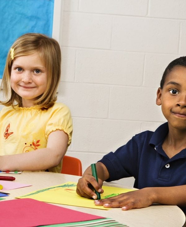 Boy and girl smiling while drawing at preschool