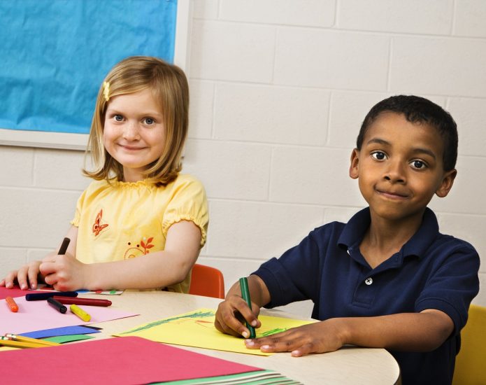 Boy and girl smiling while drawing at preschool