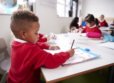 Young school boy sitting at desk doing activity