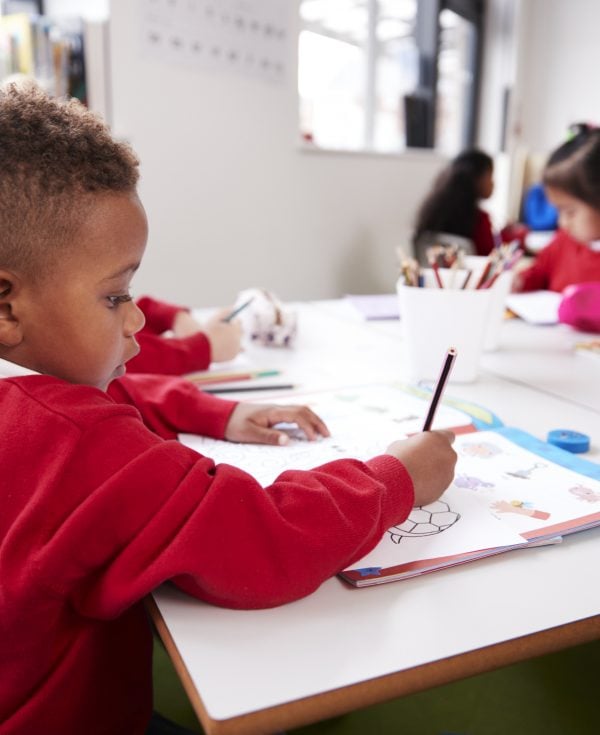 Young school boy sitting at desk doing activity