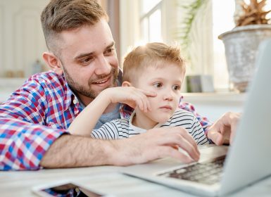 Dad watching laptop screen with son