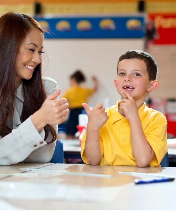 Student and teacher sitting at desk practicing counting on fingers