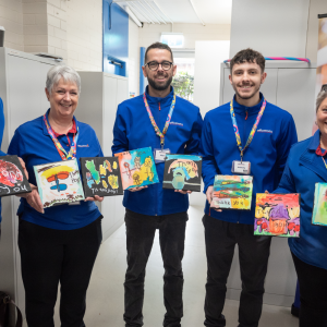 Officeworks staff holding up artworks gifted by Learning Links Preschool children