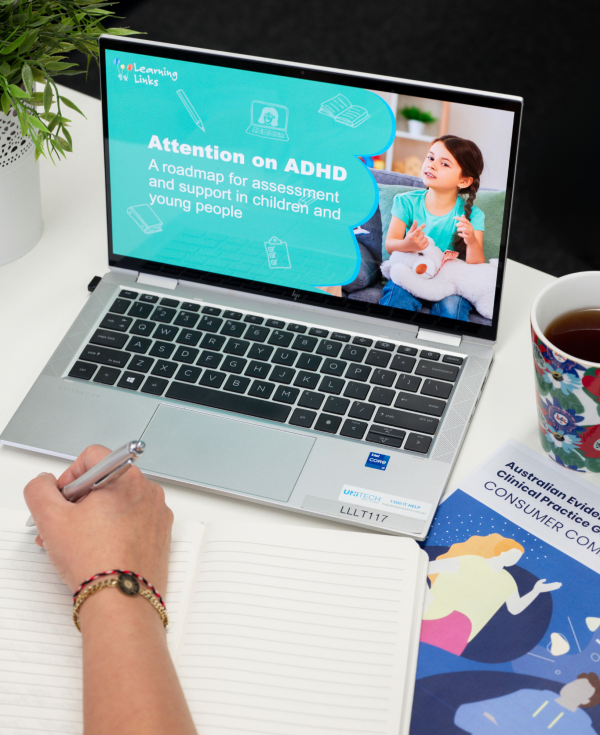 Laptop with course cover slide displayed while person's hand prepares to write notes in a book